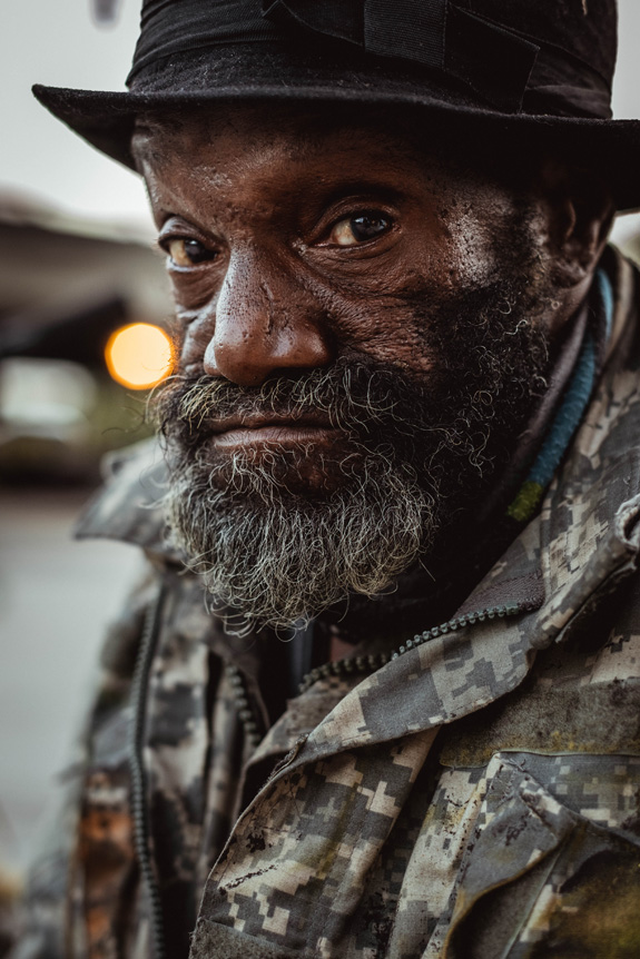 FUJIFILM Creators talk about how a lend can affect your message. Portrait photo of a man with a beard and a camouflage jacket on.