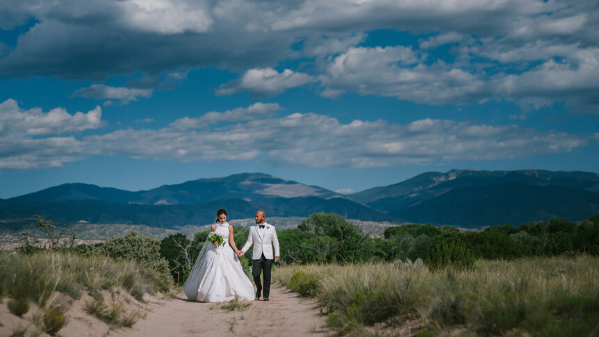 A man and woman in wedding attire standing on a desert trail