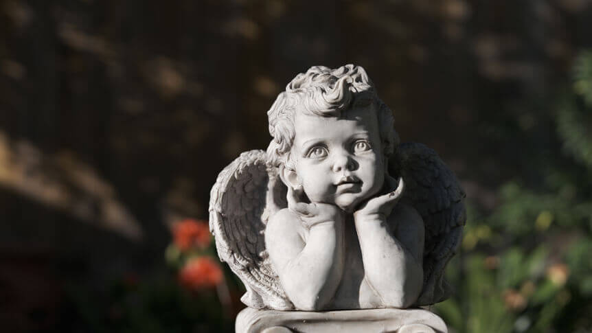 A close-up frame of a cherub statue in a garden