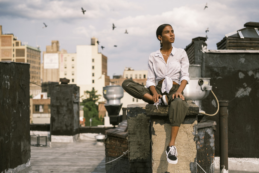 Woman sitting on New York city rooftop with flock of birds behind