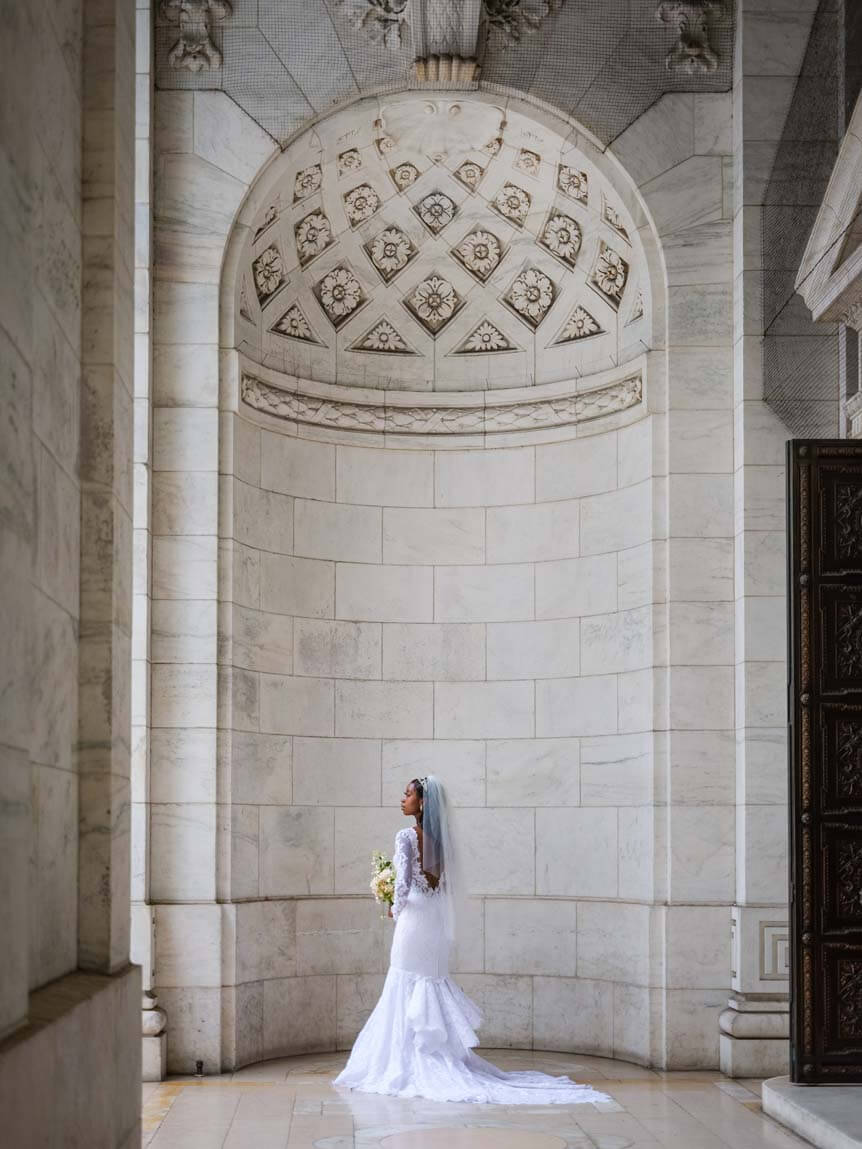 Bride in white dress standing under high archway