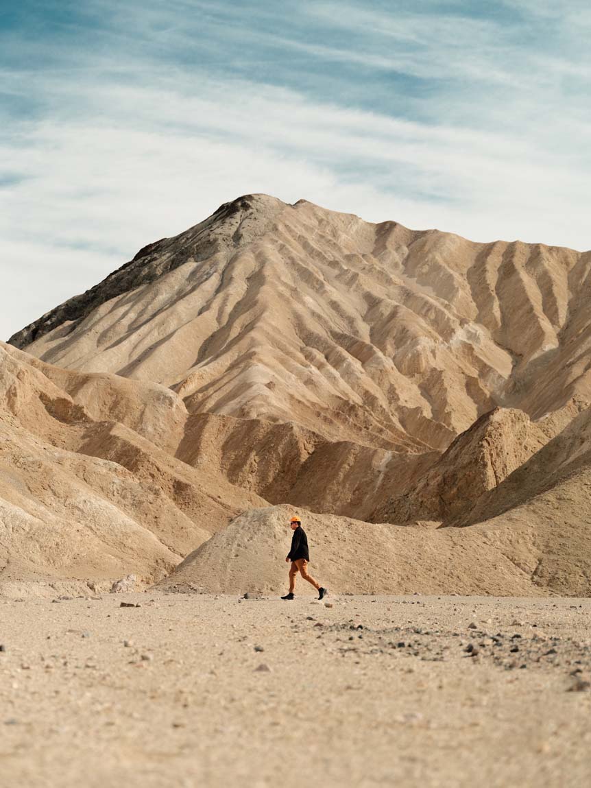 A lone figure trudges through the vast sands of Death Valley
