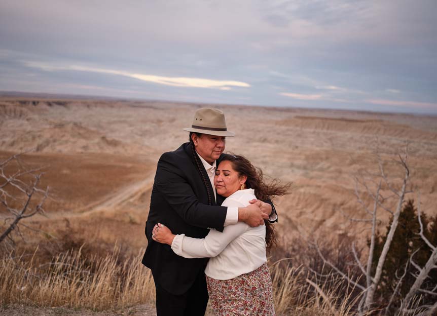 A Native American couple embrace in the sand-swept landscapes of Badlands national park