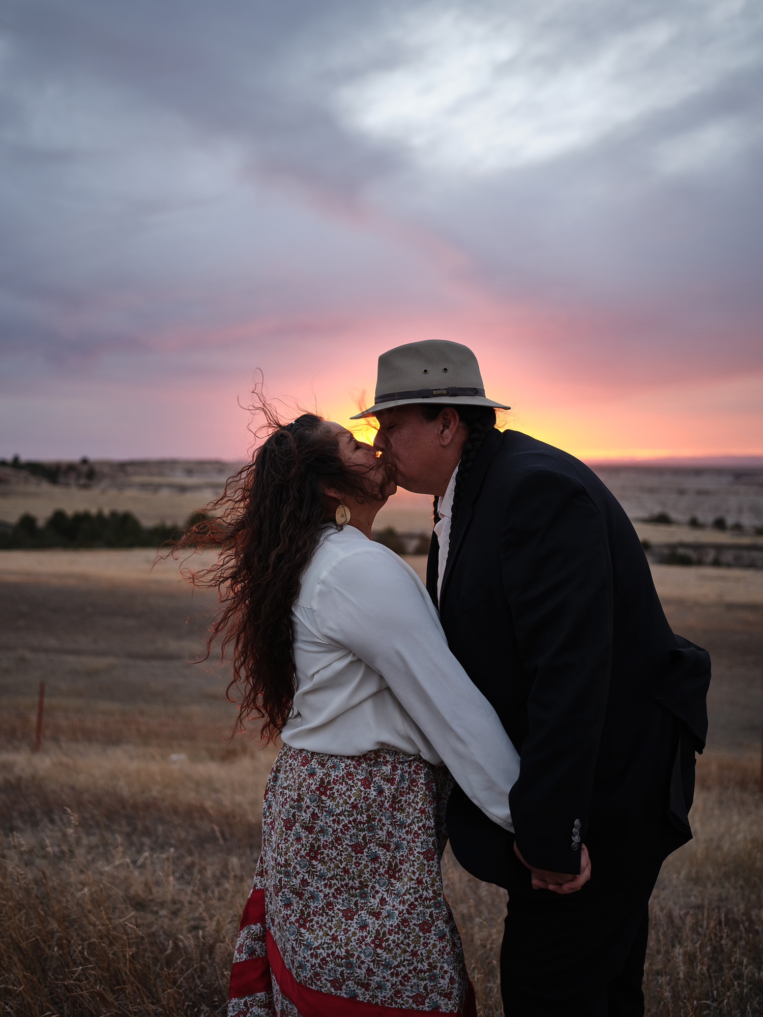 A Native American couple kiss amidst the setting sun of Badlands national park