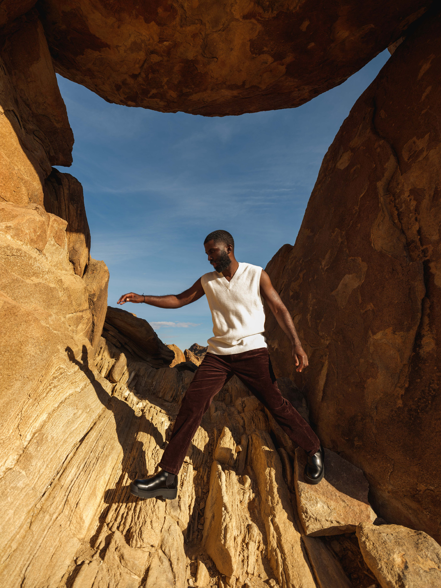 An African American man jumps across jagged rock formations
