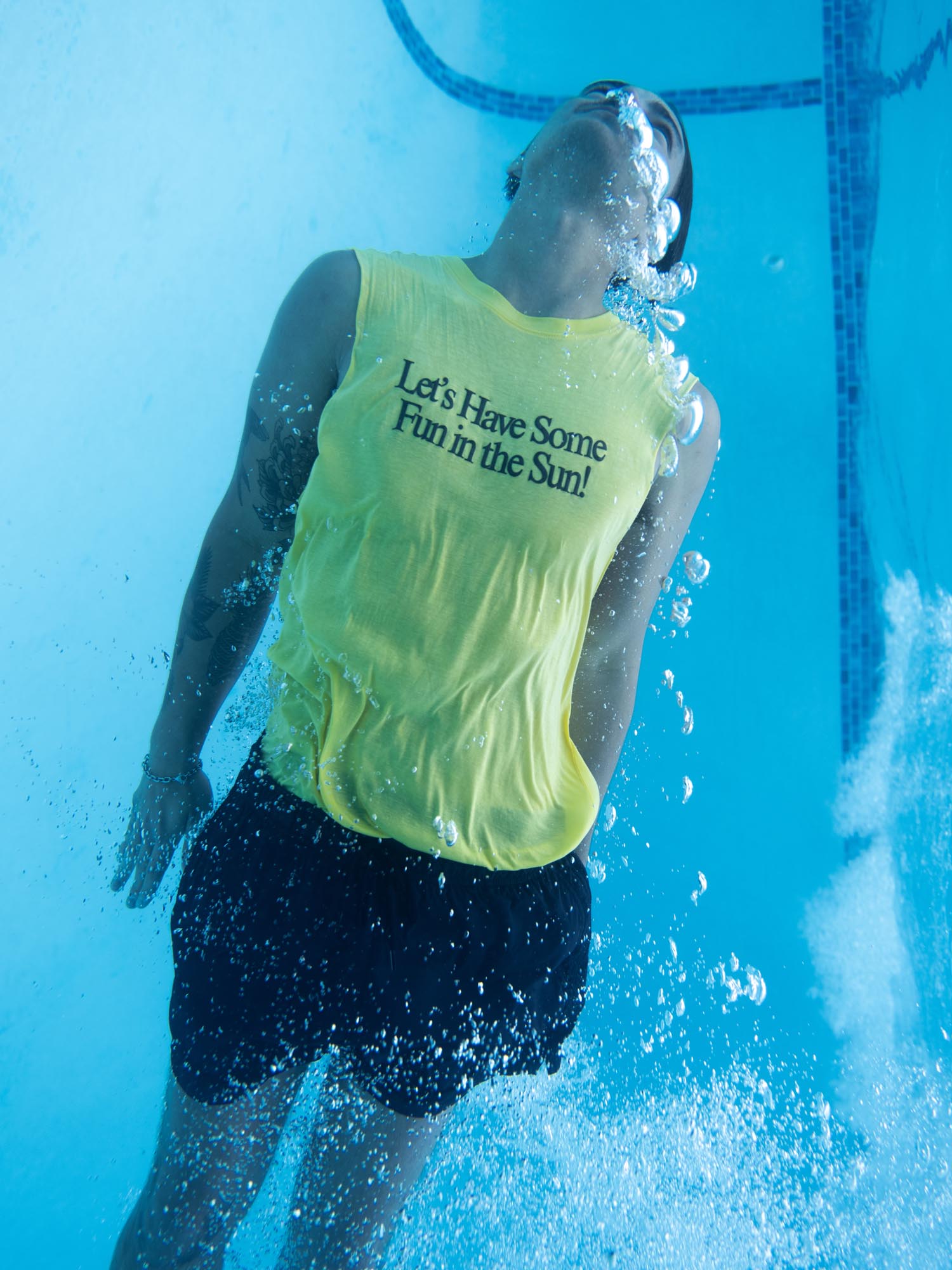 A man in a yellow tank top poses underwater