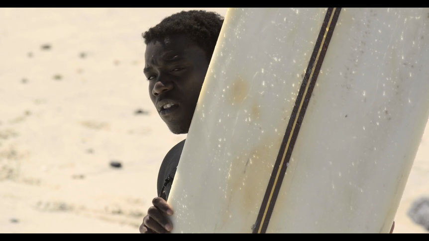 Young African-American man holding surfboard