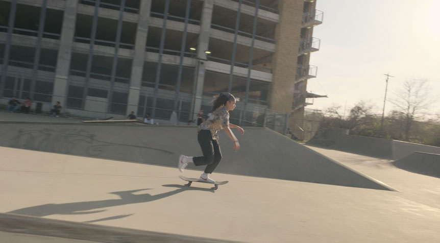 Young woman skateboarding through large, concrete skatepark