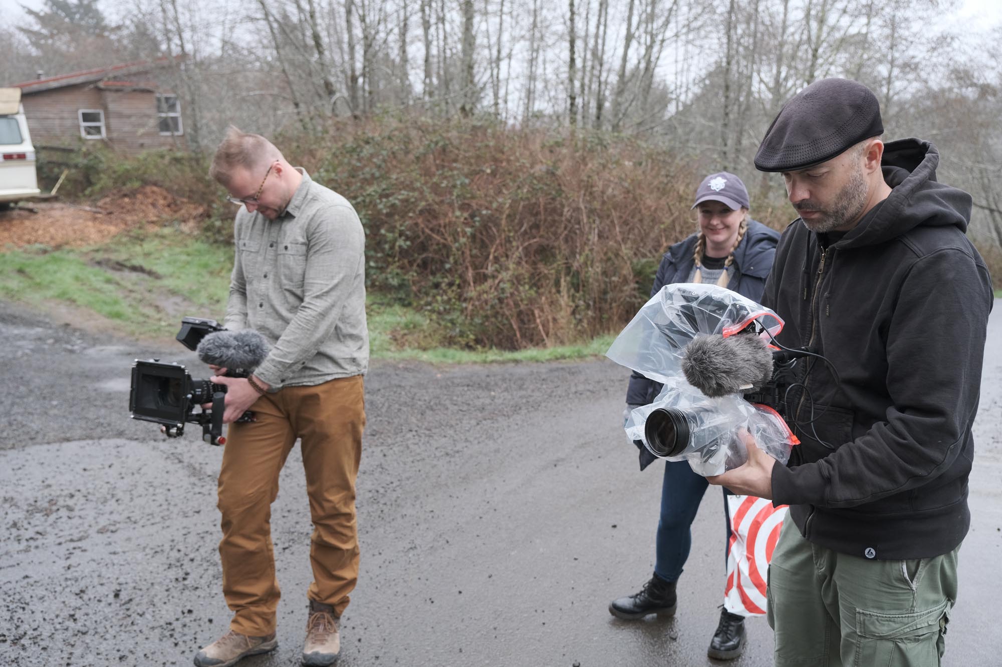 Three members of a film crew prepare for a shot on a countryside lane