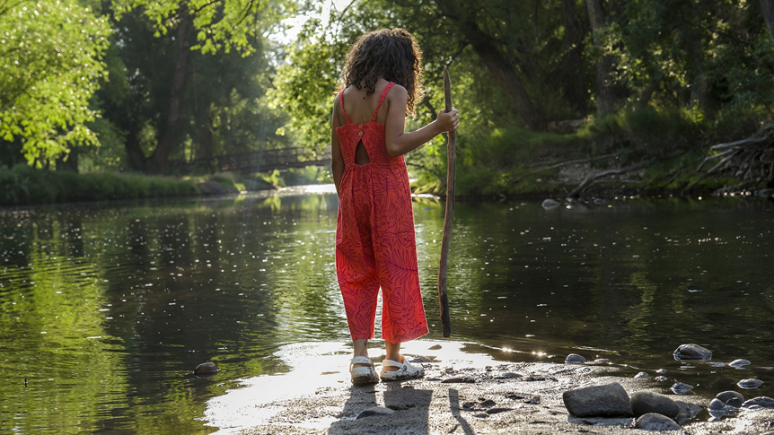 African-American woman looking down into calm stream