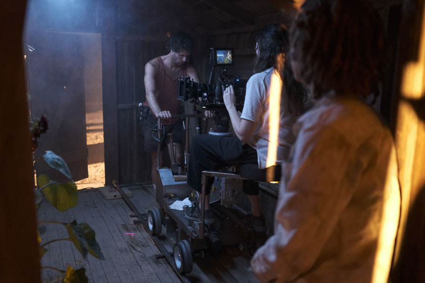 Crew moving cinema camera on dolly track inside barn