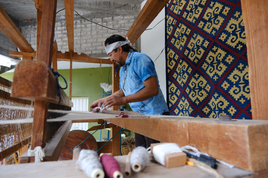 Oaxacan man weaving with loom