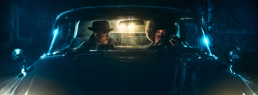 Man and a woman sitting in a car outside in the dark light