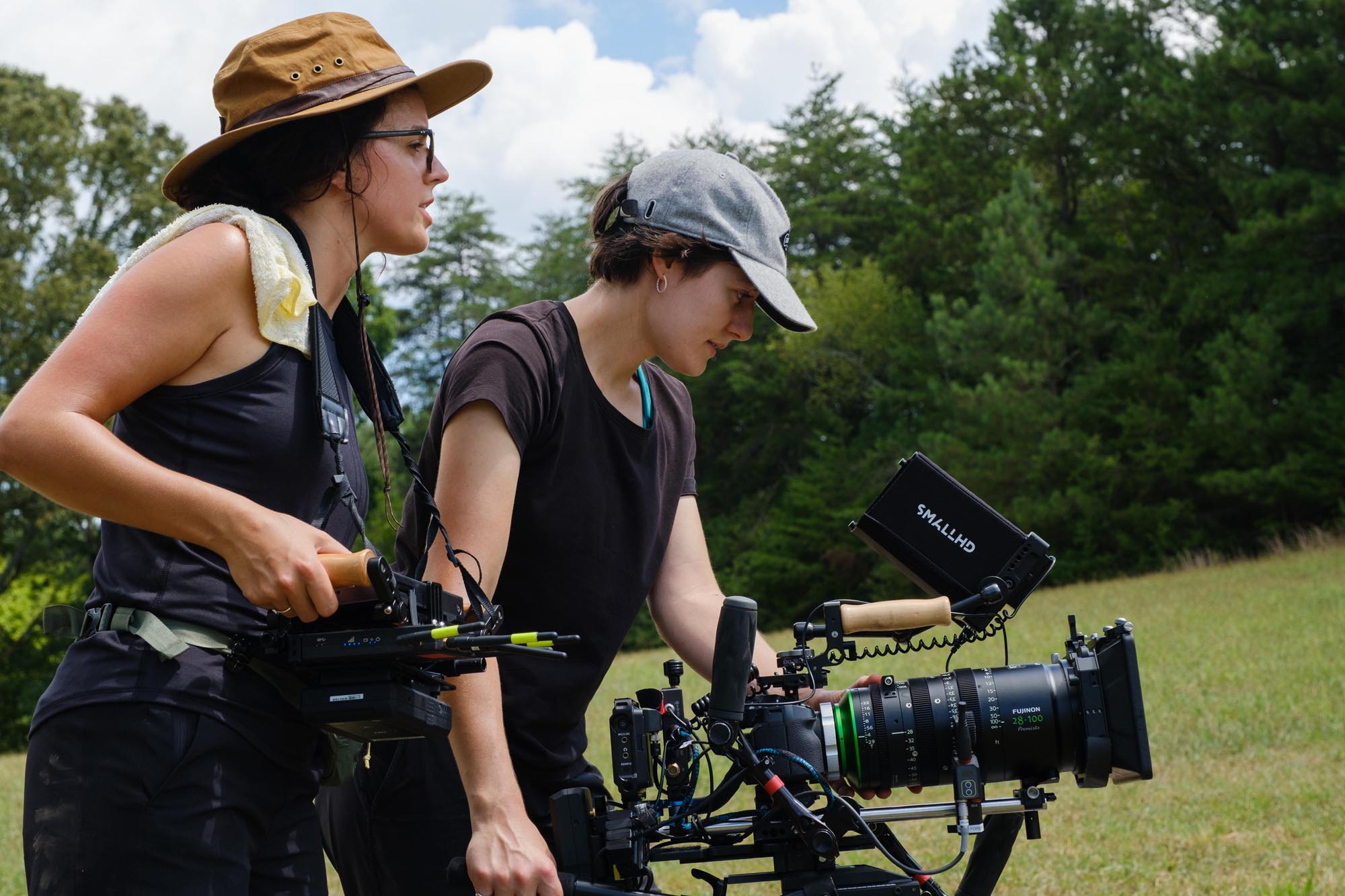 Two women set up a shot with X0H2 amidst a green field