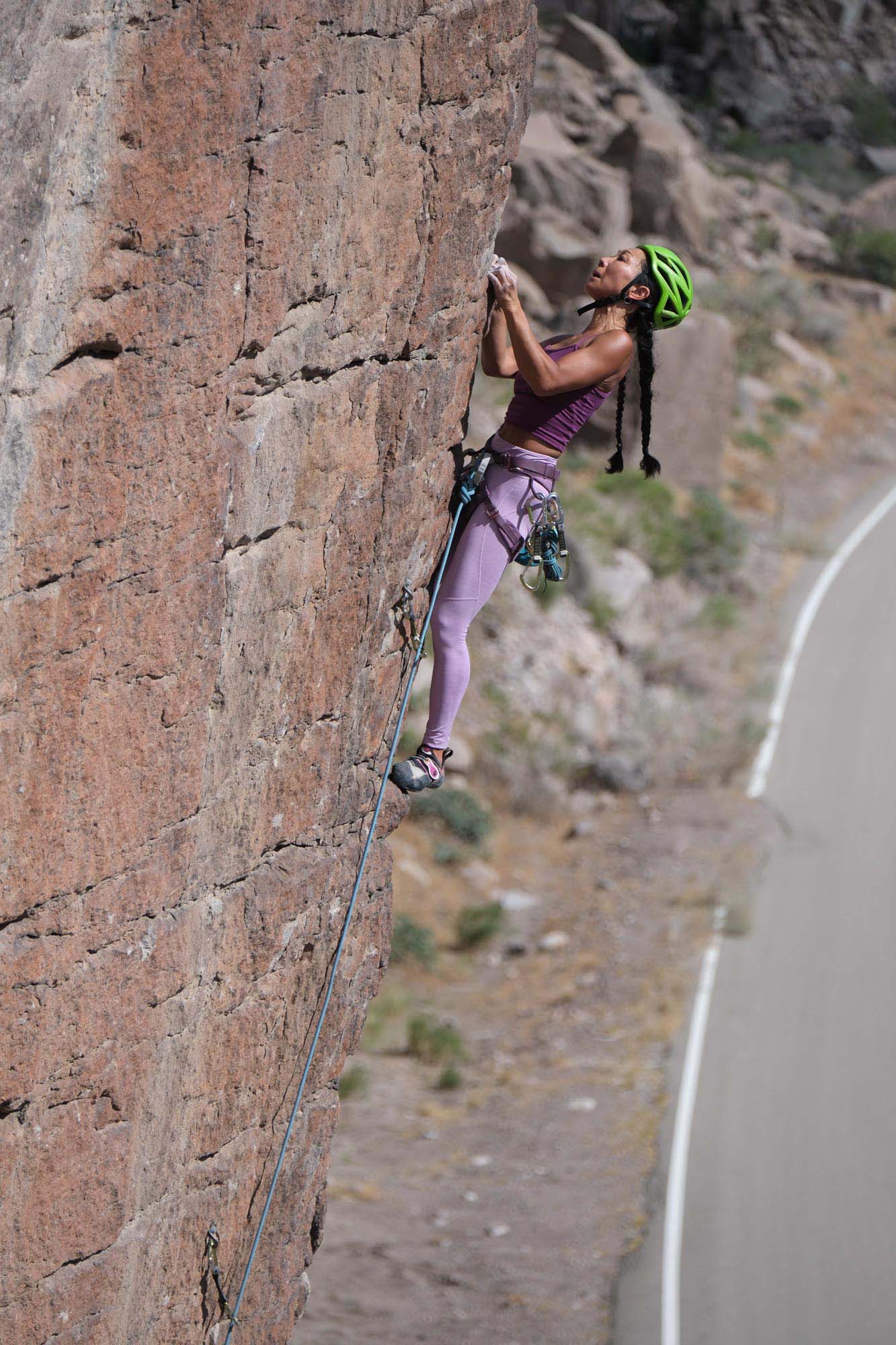 Clad in a purple track suit, a woman scales a rock face