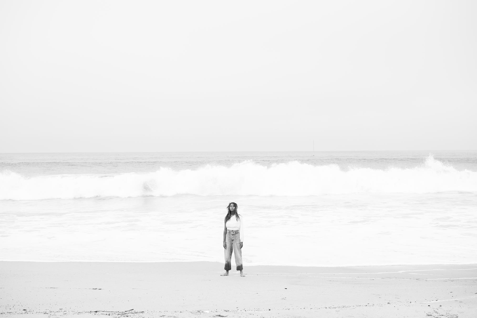 A young black woman stands framed against a tumultuous wave formation