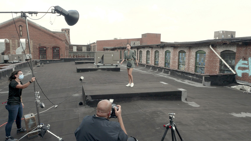 Young woman model being photographed under lights on rooftop