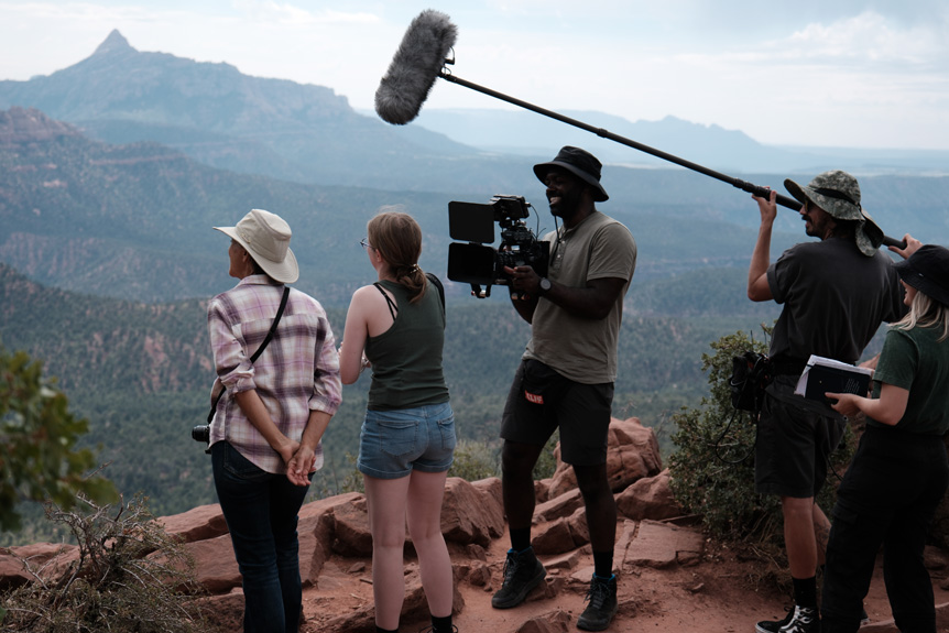 Two women admiring valley landscape with camera crew surrounding