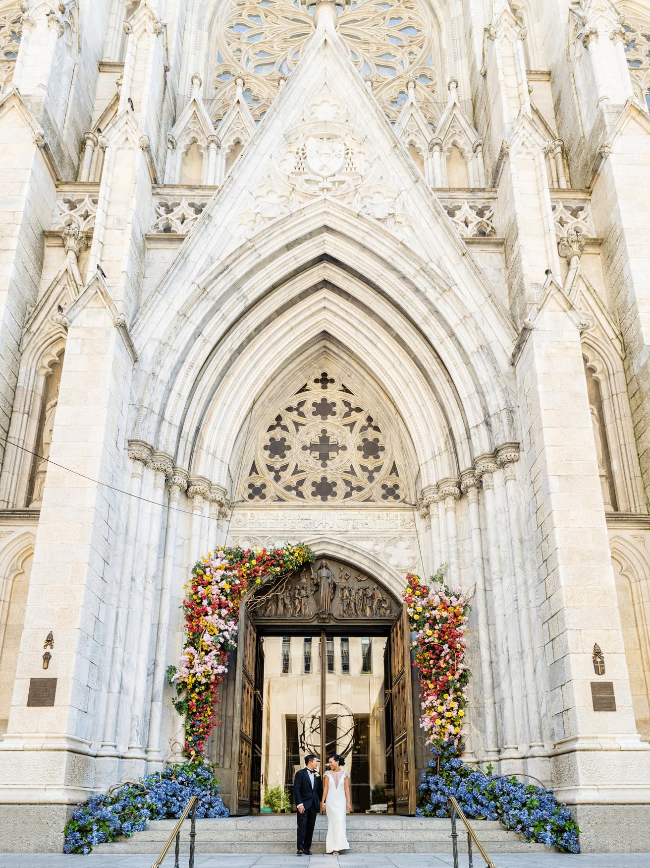 A wide shot of a Filipino couple, posing for wedding photos outside a cathedral