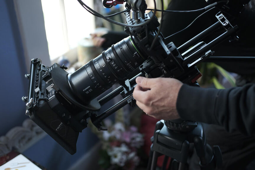 Close up of camera operator filming with FUJIFILM X-H2S movie camera rig on tripod.