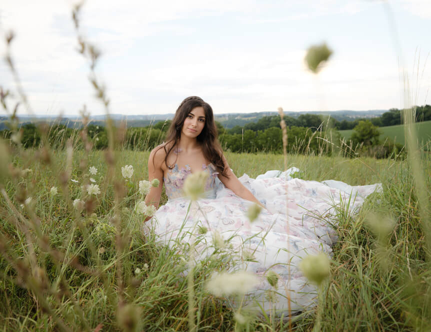 Bride sitting in grassy field