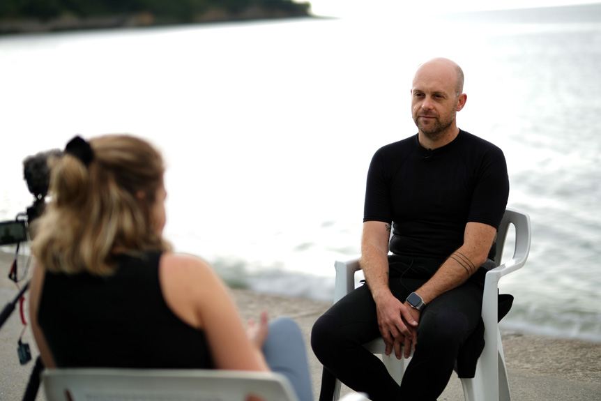Man being interviewed by young woman director at beach