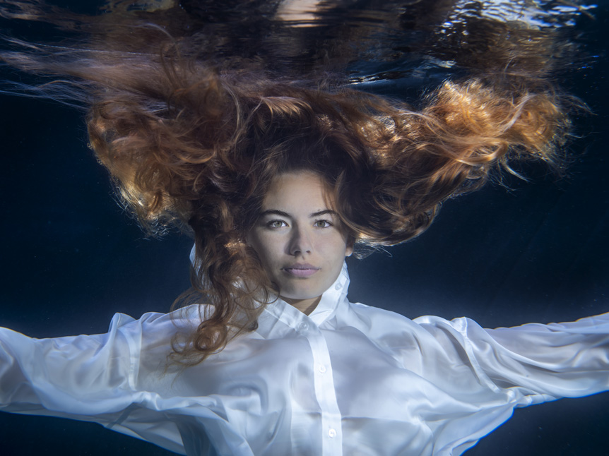 Young woman with long hair and flowing white shirt underwater
