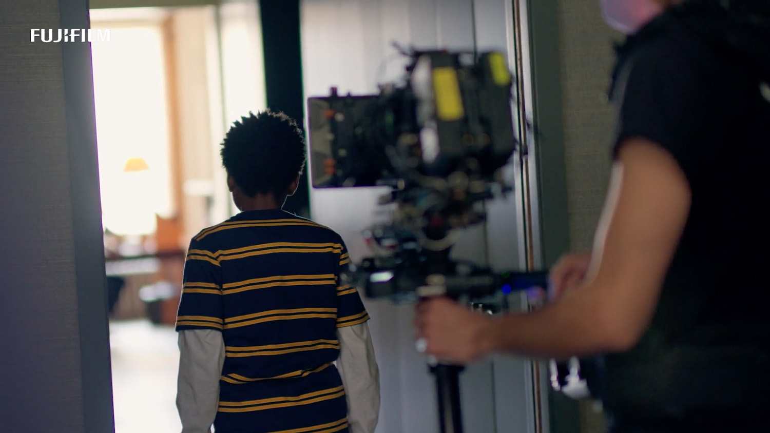 Handheld camera follows young boy actor through corridor