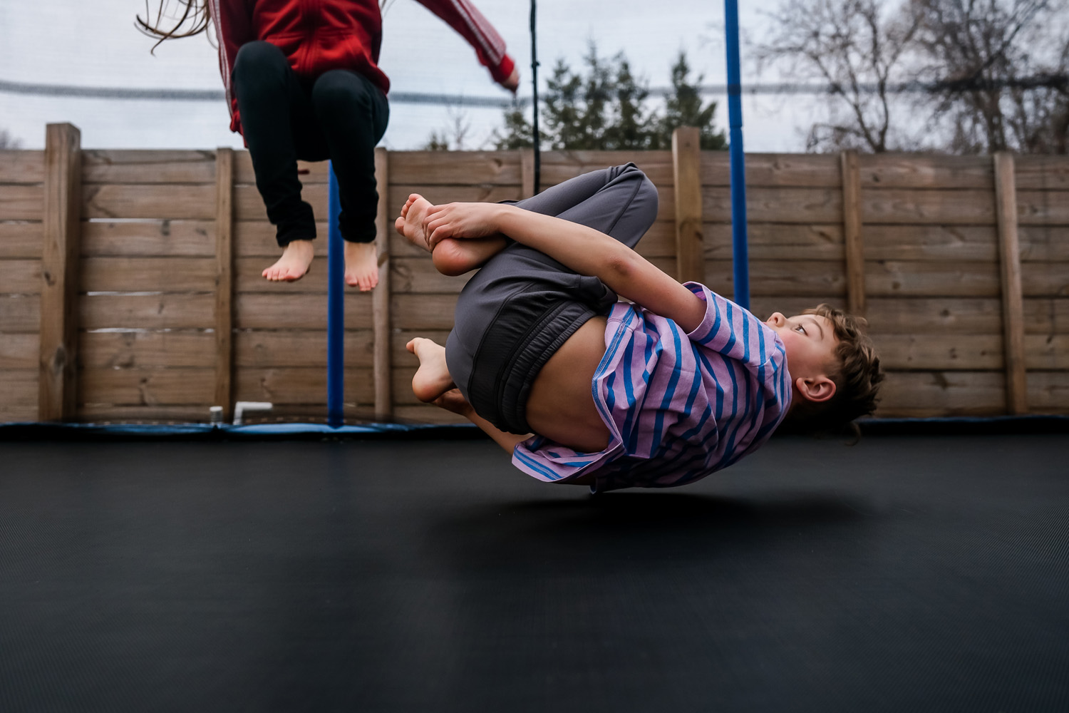 Boy in mid air bouncing on a trampoline while in the foetal position