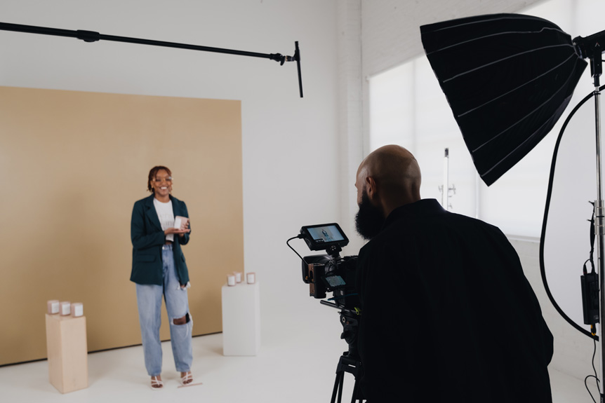 Small business owner poses for a photograph with professional photographer in from of a beige and white backdrop