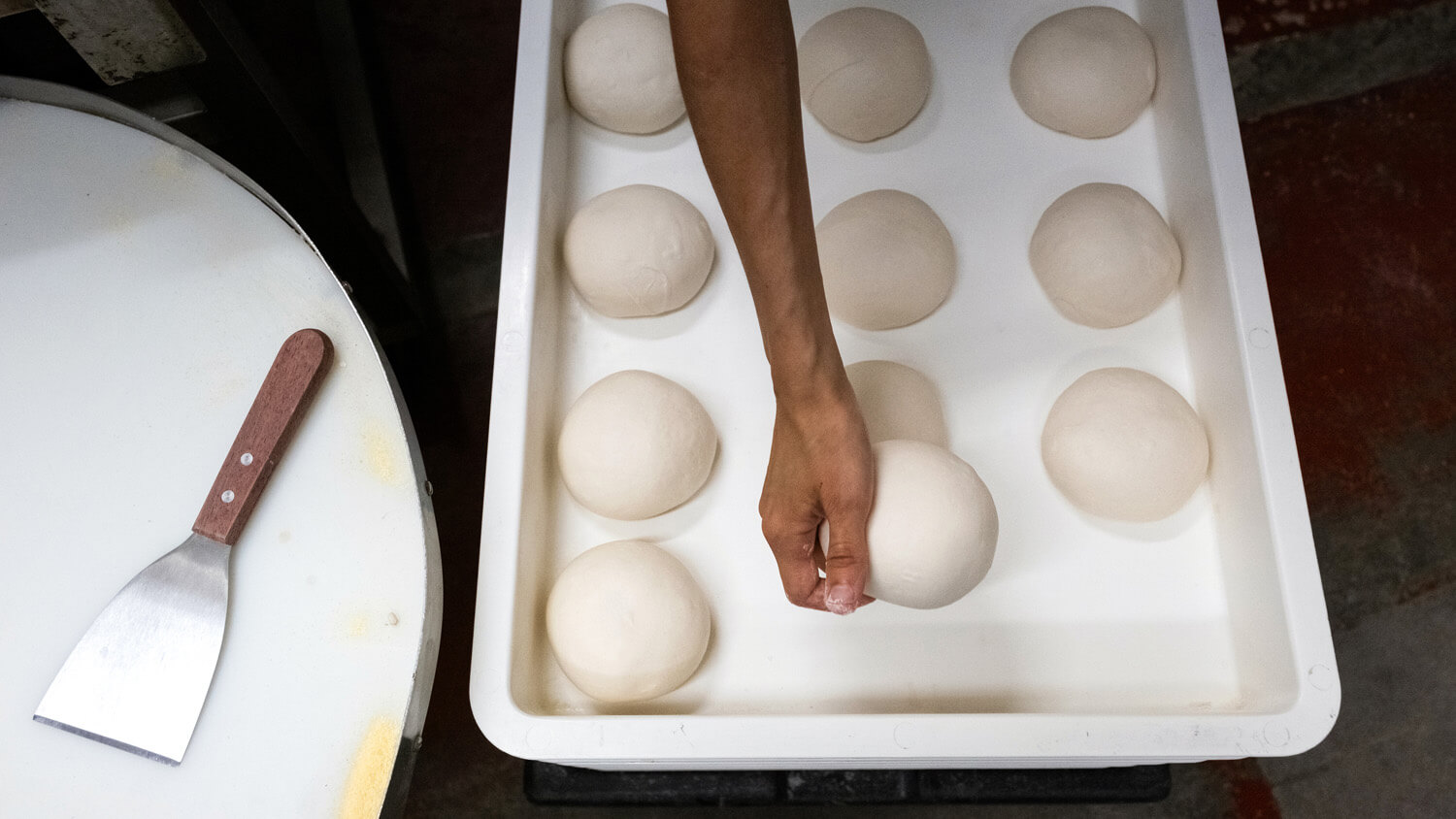 flat lay of balls of pizza dough being laid on metal tray