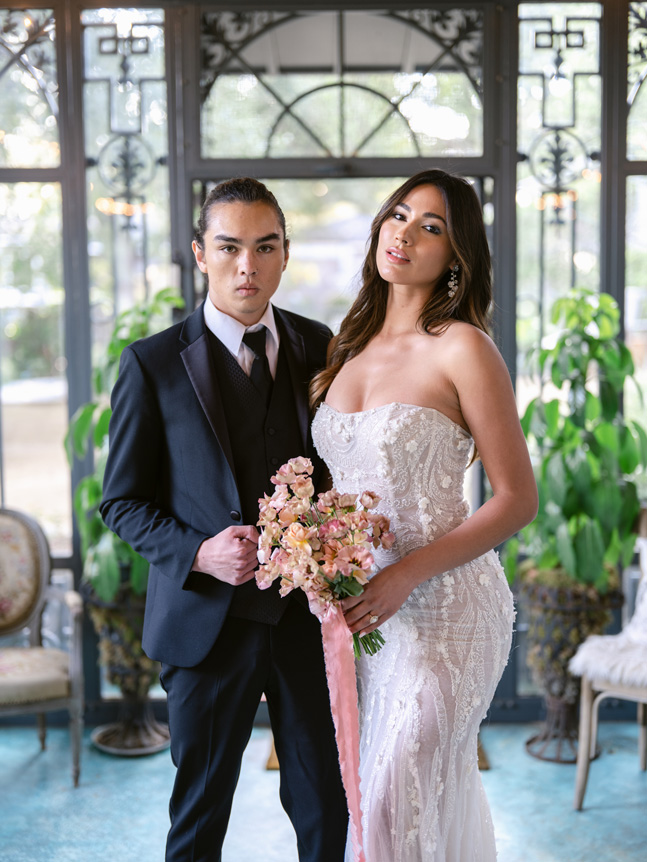 Bride and groom posing in lobby with bouquet of flowers
