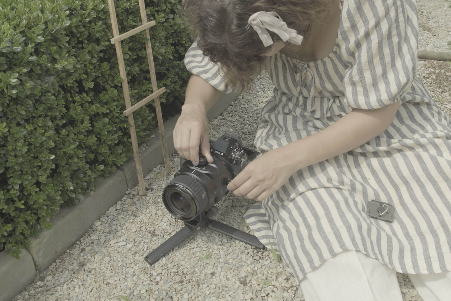 Woman setting up camera for photoshoot in garden
