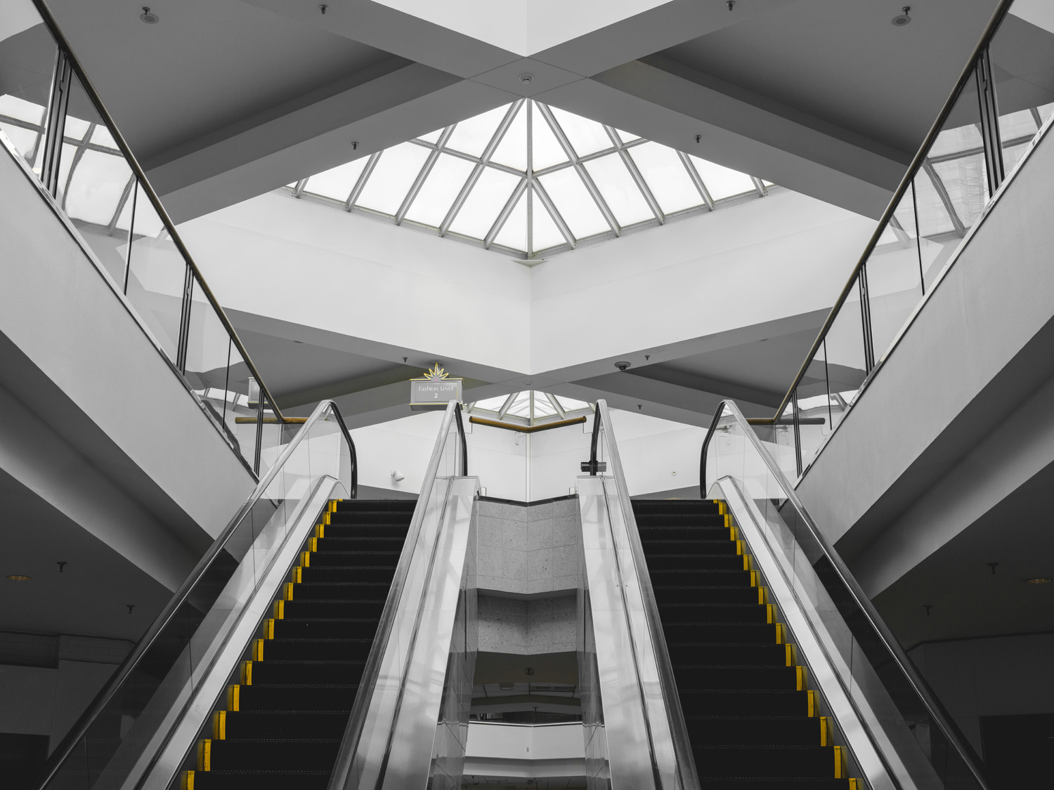Photograph of symmetrical escalators in grey building