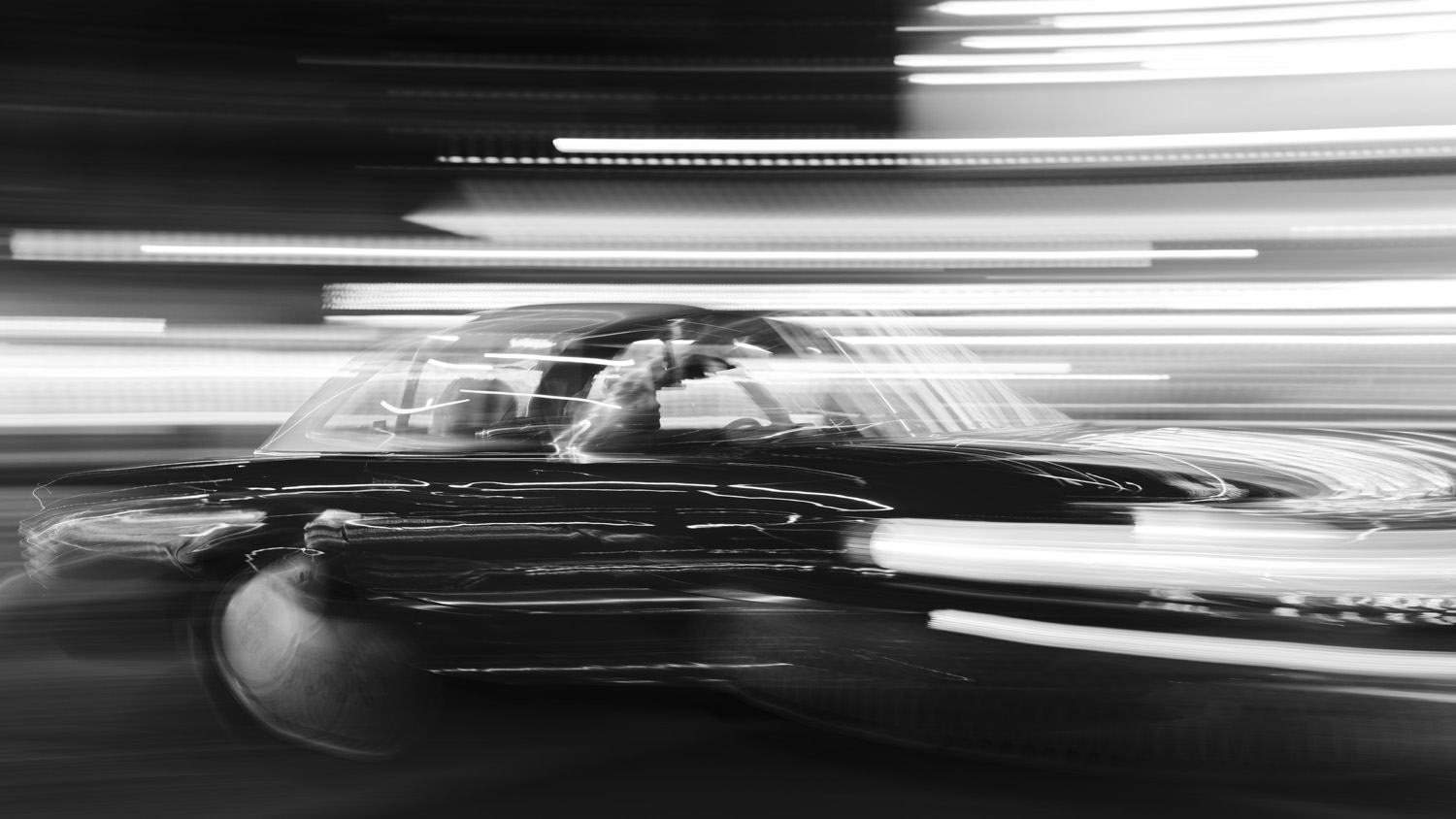 Black and white long exposure photo of a car travelling with blurred effect