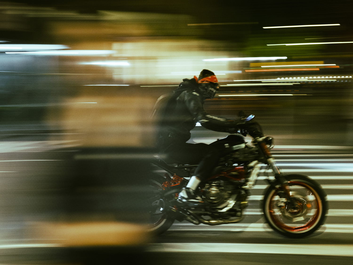 motorcyclist moving through city street at night creating motion blur