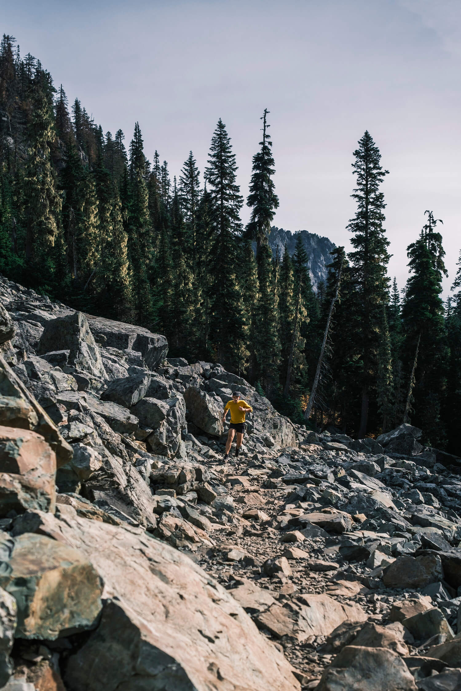 man runs on trail through rocky mountainside