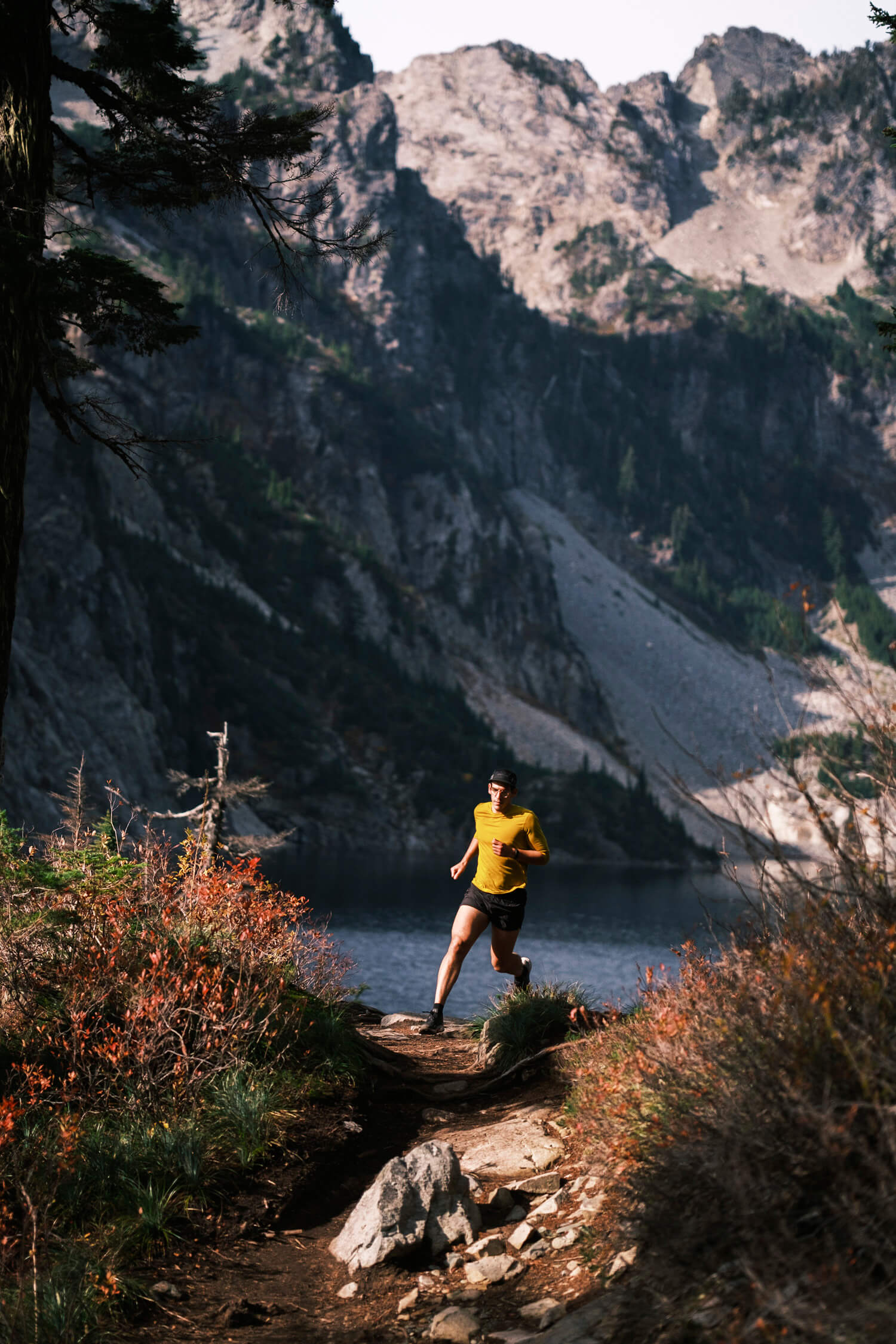 trail runner turning a corner with lake and mountains in background