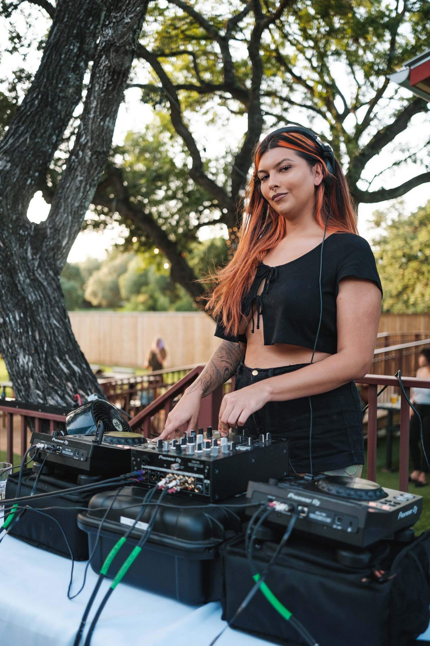 Young woman with orange hair behind outdoor DJ booth