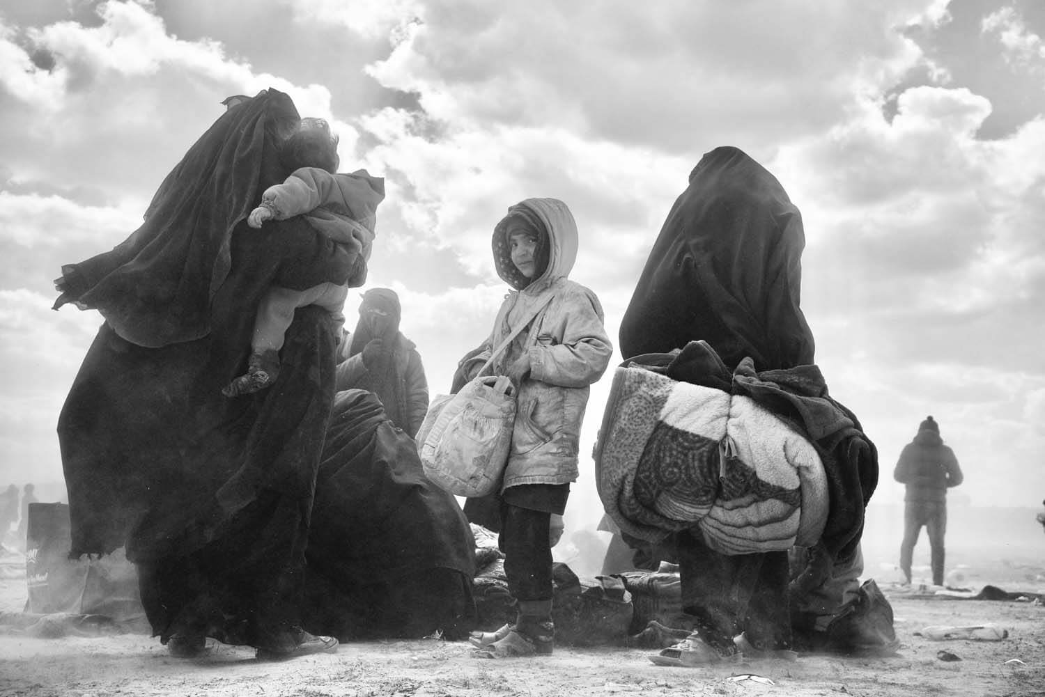 Young Syrian girl standing between women holding luggage