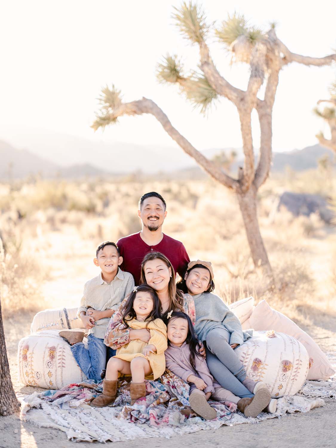 A smiling family of six crowd together, smiling amidst golden sunlight